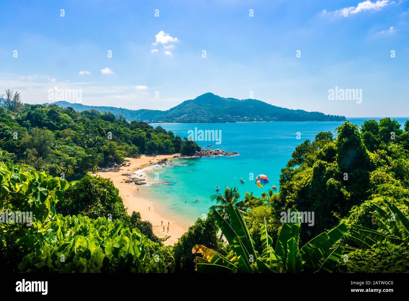 Point de vue sur la plage de Kamala, Phuket, Thaïlande par une journée ensoleillée avec le ciel bleu, les montagnes en arrière-plan et une plage, la mer et les arbres en premier plan Banque D'Images