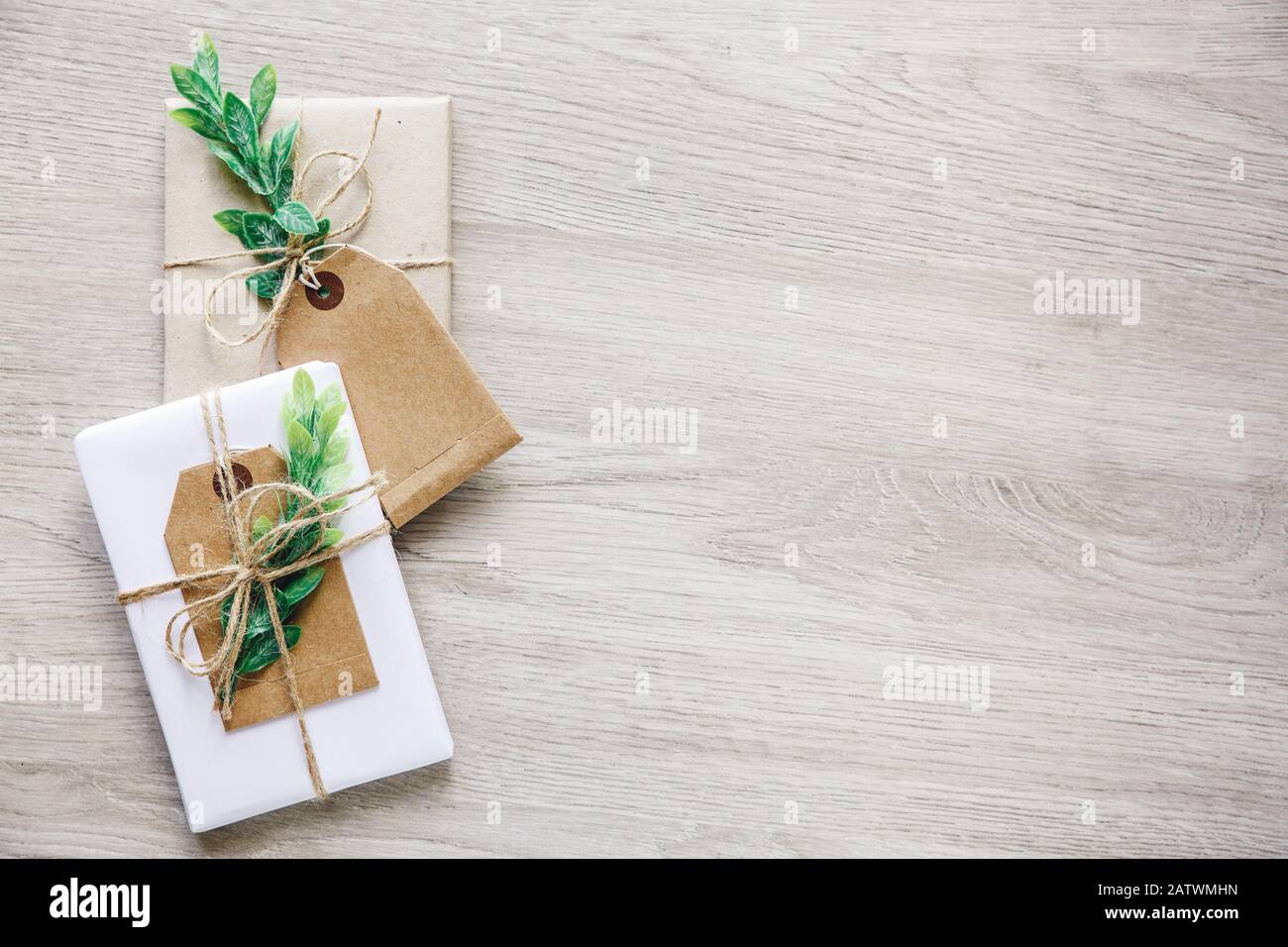 Composition avec boîtes cadeaux de style naturel artisanales, éléments de décoration florale et noeud de ficelle rustique sur fond en bois. Banque D'Images