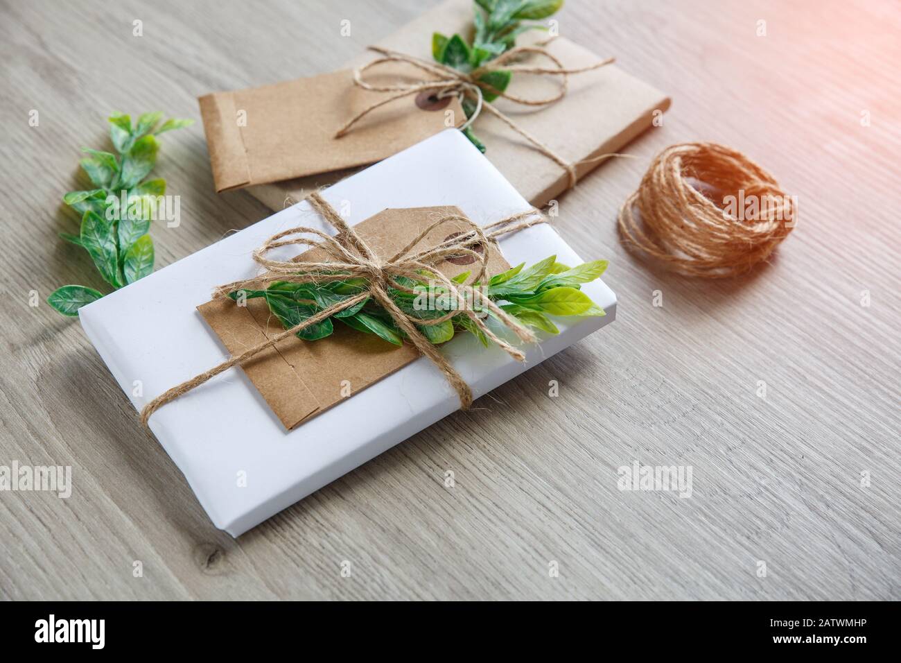 Composition avec boîtes cadeaux de style naturel artisanales, éléments de décoration florale et noeud de ficelle rustique sur fond en bois. Banque D'Images