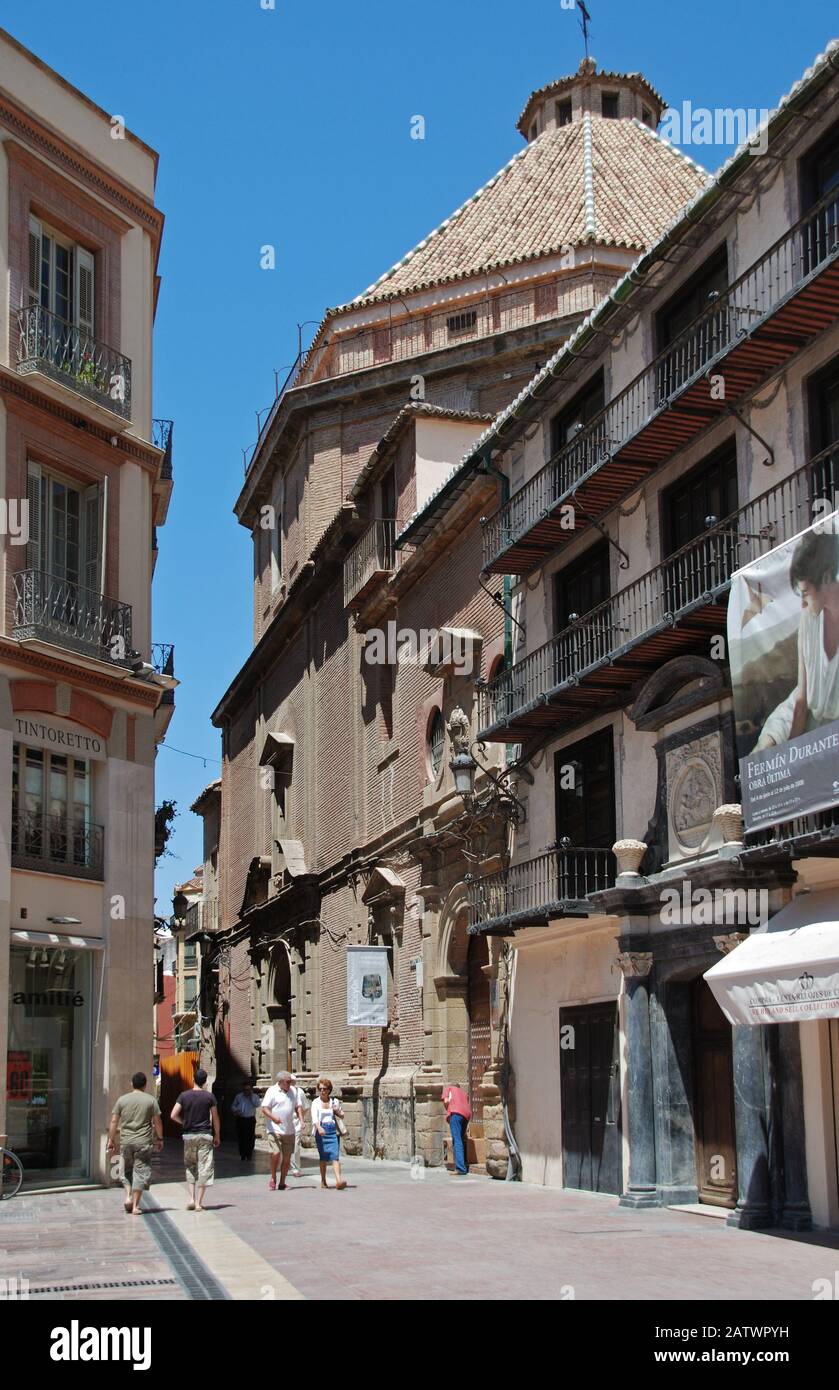 Vue sur l'église Saint-Christ de la Santé dans le coin nord-ouest de la place de la Constitution avec des gens qui apprécient le cadre, Malaga, Espagne. Banque D'Images