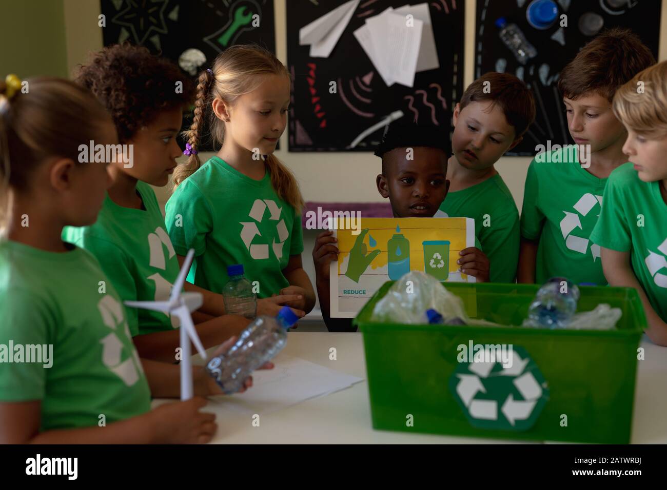 Groupe d'écoliers portant des t-shirts verts avec un logo de recyclage blanc sur eux debout autour d'un Banque D'Images