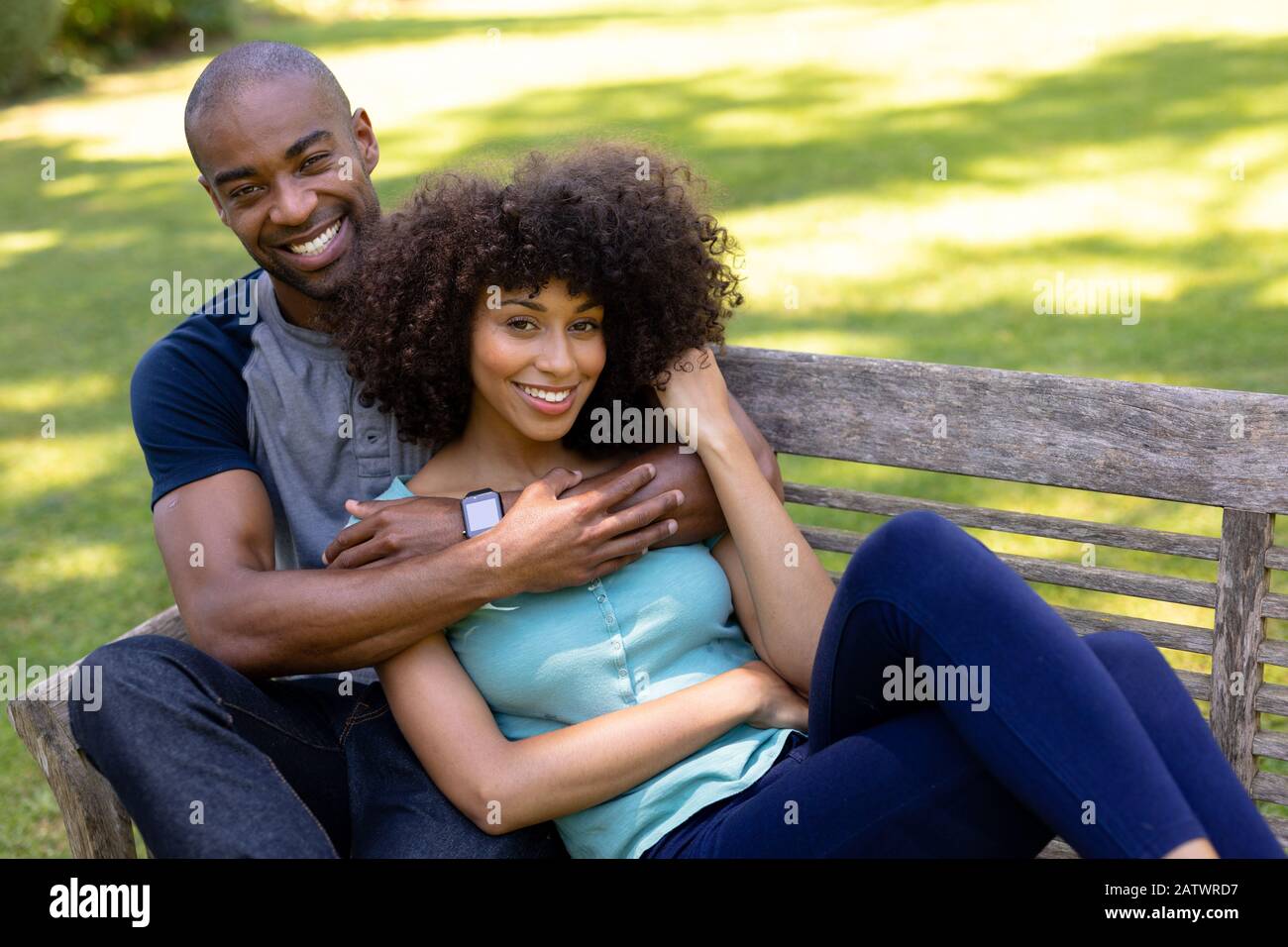 Un jeune couple heureux assis sur un banc dans le jardin Banque D'Images