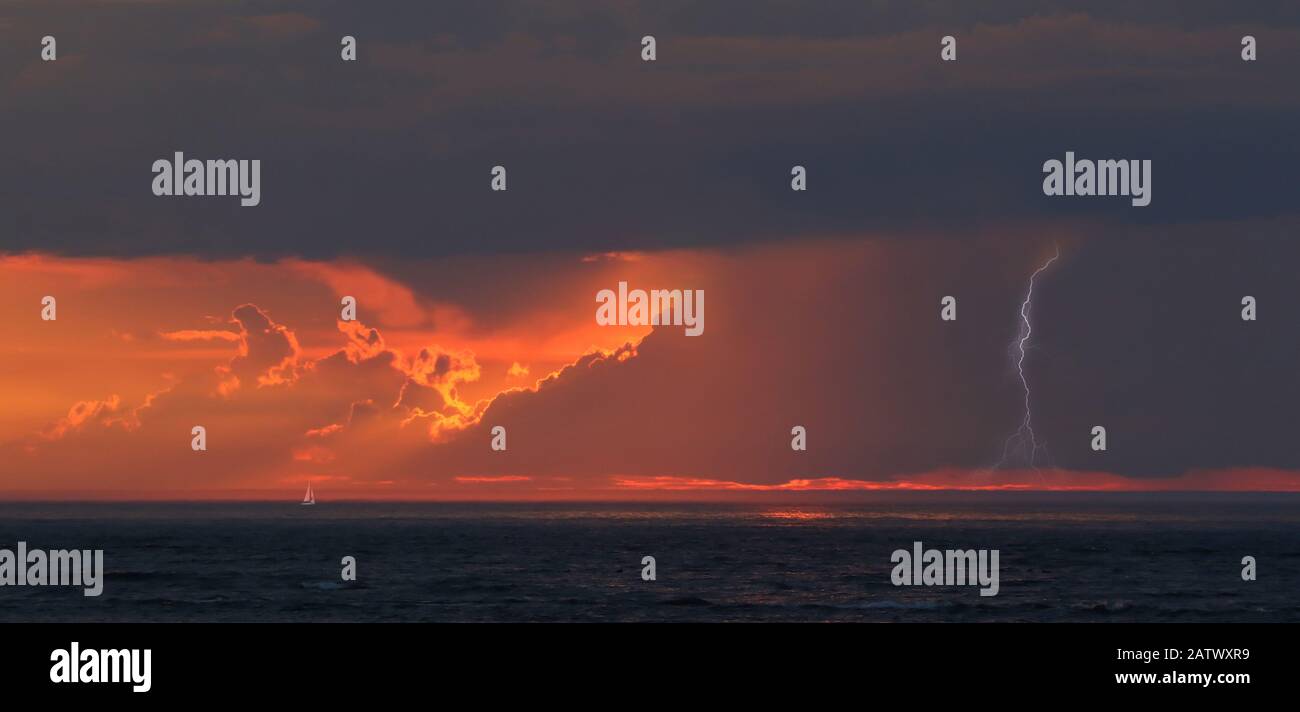 Voile bateau en mer et tempête au coucher du soleil avec la foudre Banque D'Images