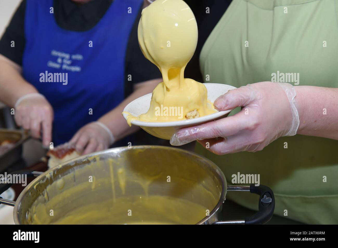 La crème est versée sur un pudding chaud dans un centre pour les personnes âgées, Leeds UK Banque D'Images