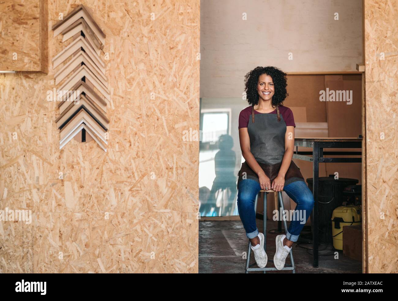 Jeune femme souriante assise dans son atelier de cadrage Banque D'Images