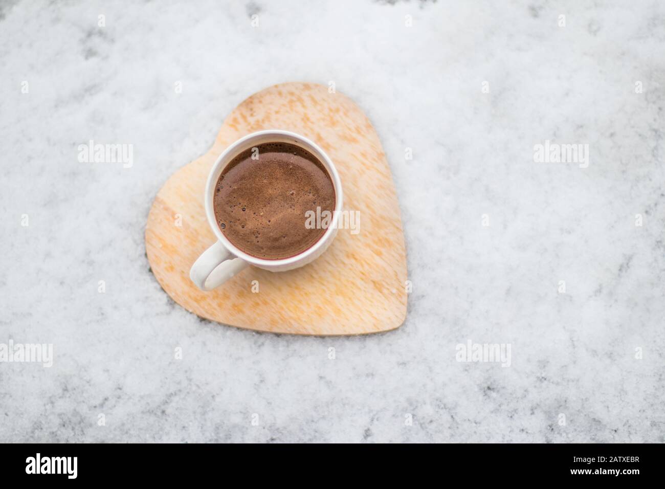 Du café sur un dessous de verre en bois dans la neige en hiver. Banque D'Images