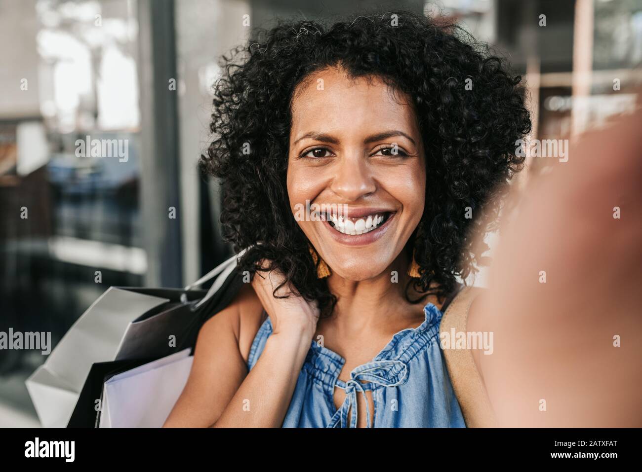 Jeune femme souriant et prenant un selfie tout en dehors des achats Banque D'Images