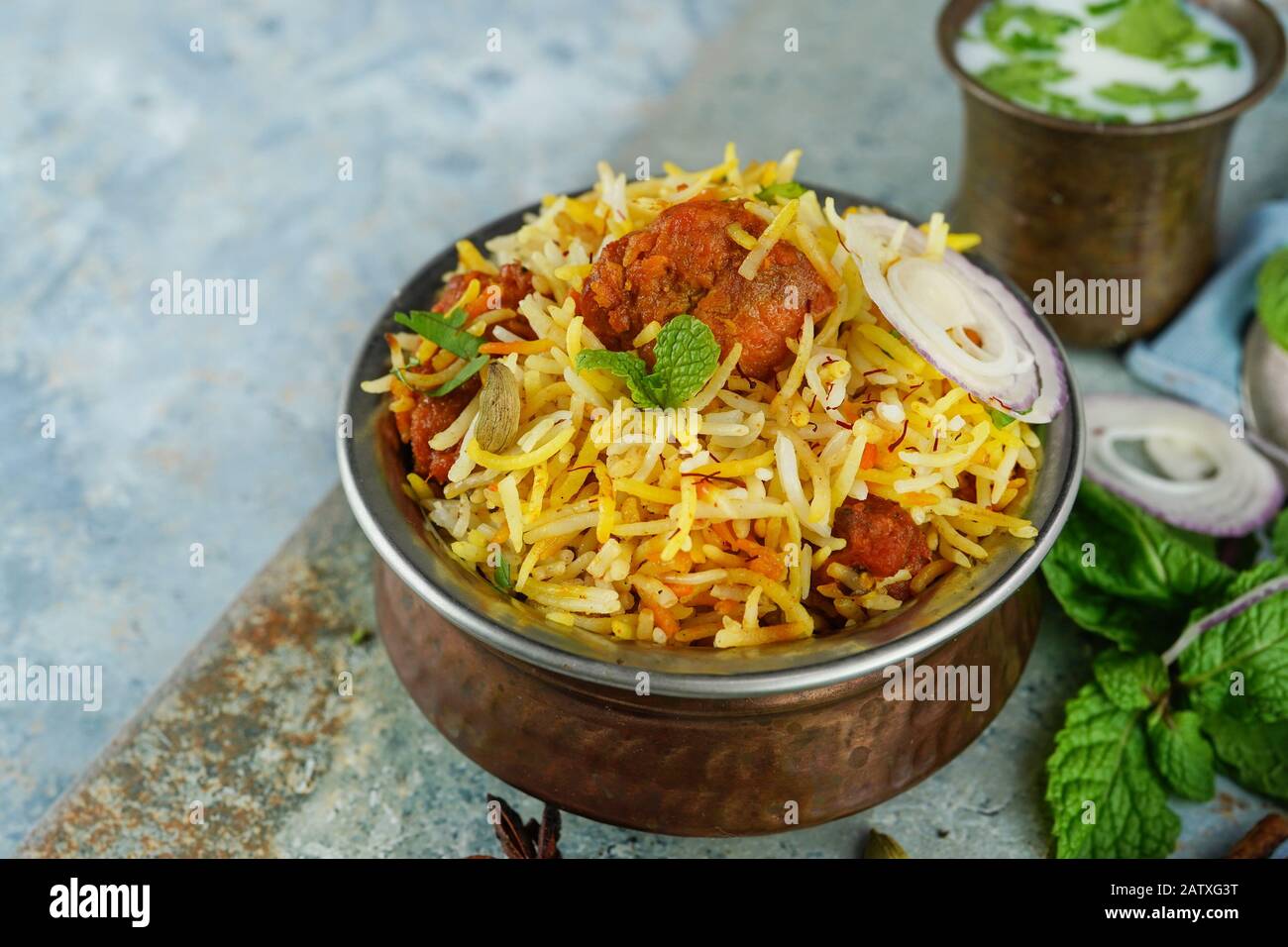 Tikka Biryani de poulet maison servi dans un récipient traditionnel en laiton avec sauce au yaourt, foyer sélectif Banque D'Images