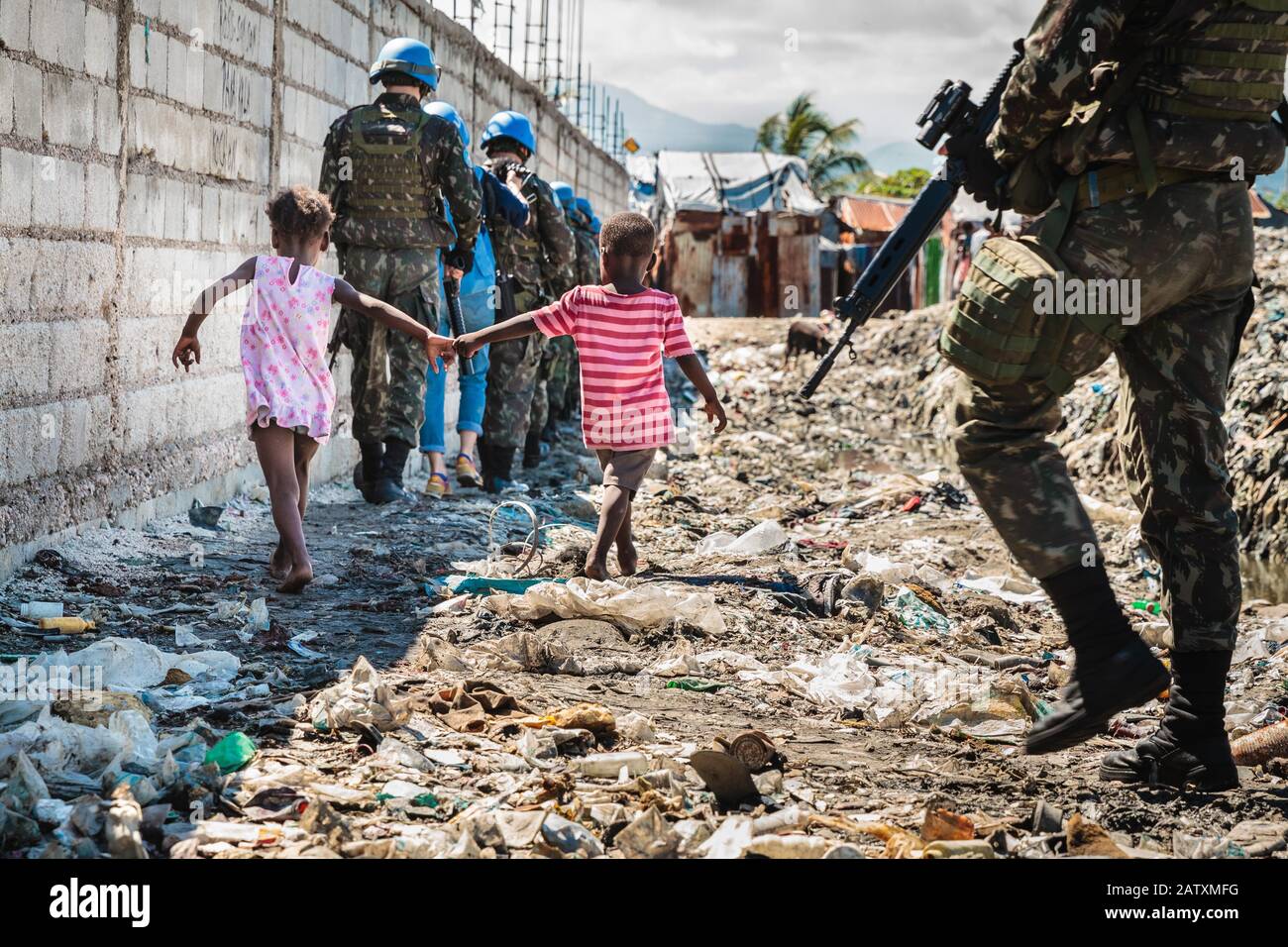 Deux enfants et une patrouille des Nations Unies, casques bleus, promenade dans les ordures, Cité Soleil, Port-au-Prince, Ouest, Haïti Banque D'Images