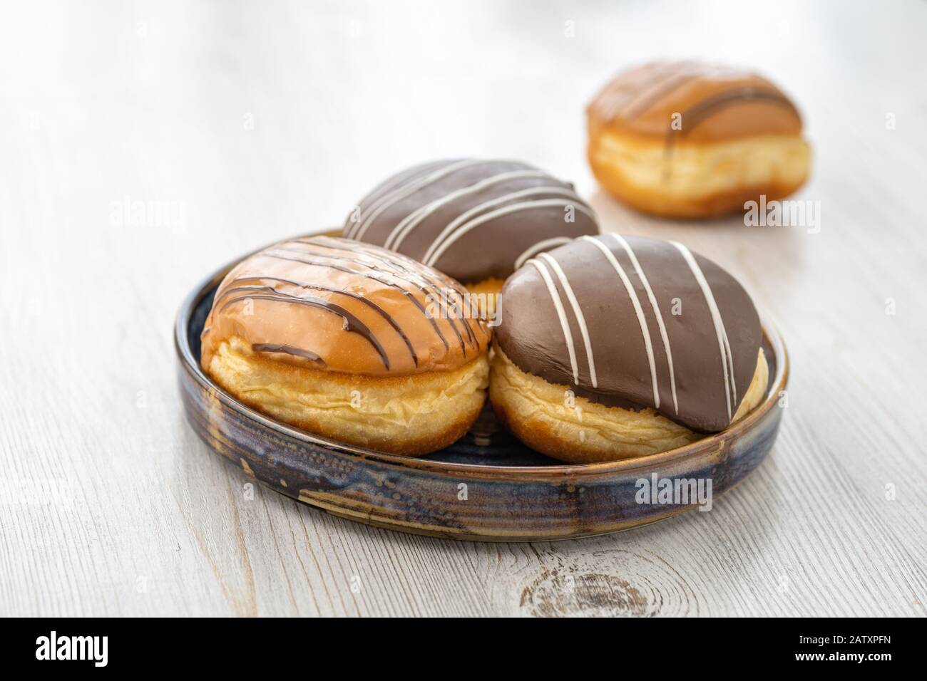 Beignet ou pain à base de pâte de levure douce farcie de chocolat ou de crème avec glaçage. Confiseries - Berliner Pfannkuchen. Banque D'Images