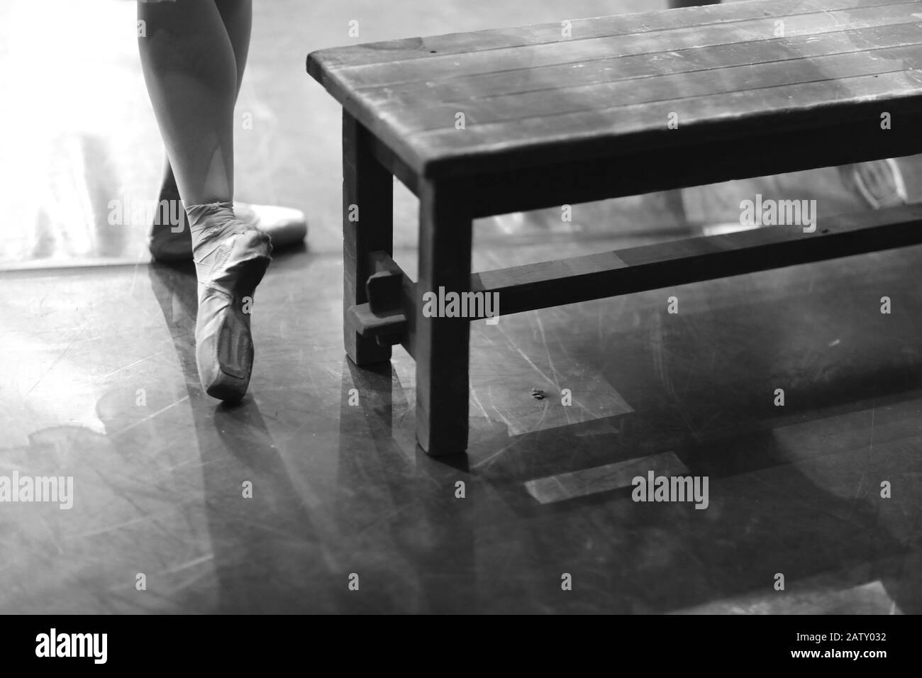 Les pieds d'une ballerine à pointe debout dans une salle de répétition près d'un banc en bois Banque D'Images