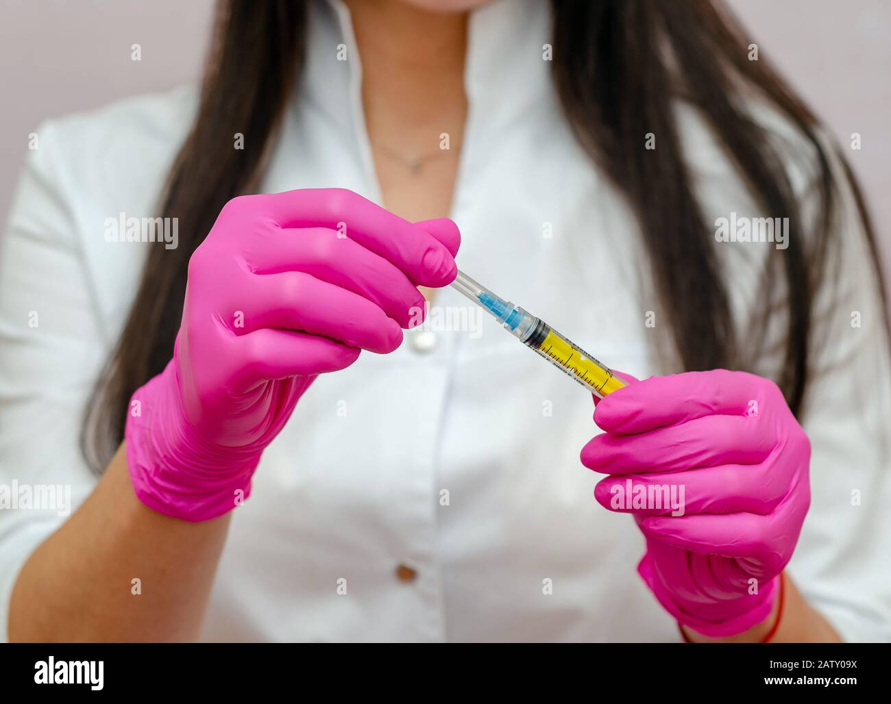 Une femme médecin avec des cheveux noirs et des gants violettes montre une  seringue Photo Stock - Alamy