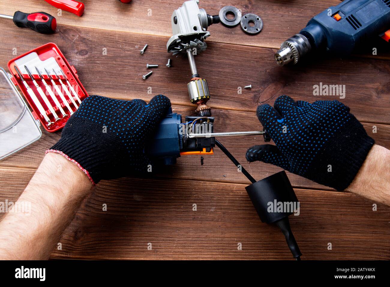 Le maître à réparer un appareil électrique cassée : perceuse, cutter sur  une table en bois. Atelier de réparation d'outils électriques Photo Stock -  Alamy