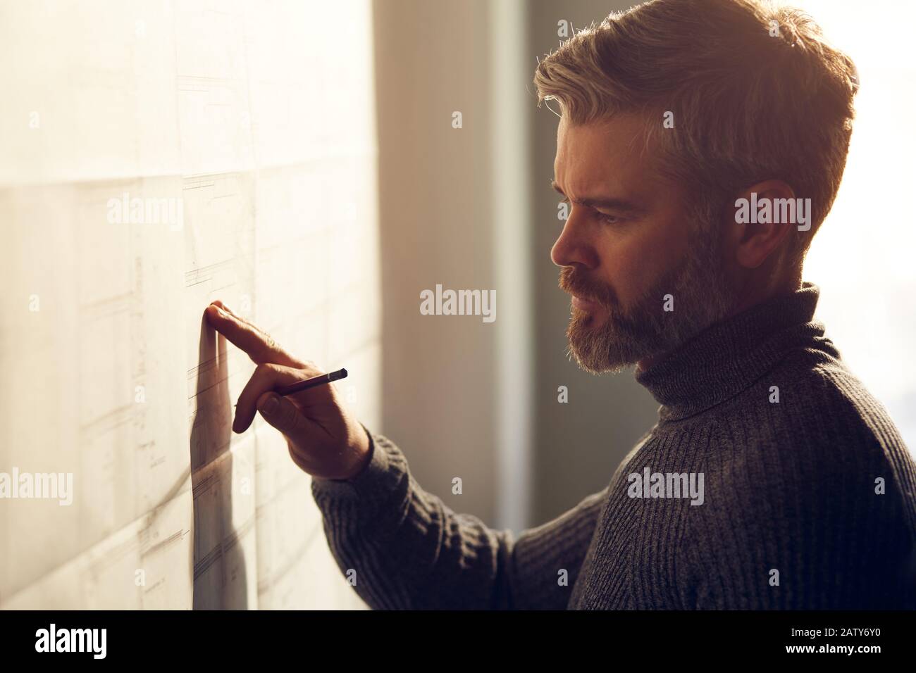 Gros plan portrait de beau homme concentré sur le travail. Architecte travaillant au bureau avec des plans. Concevoir un projet de construction par un ingénieur. Arche Banque D'Images