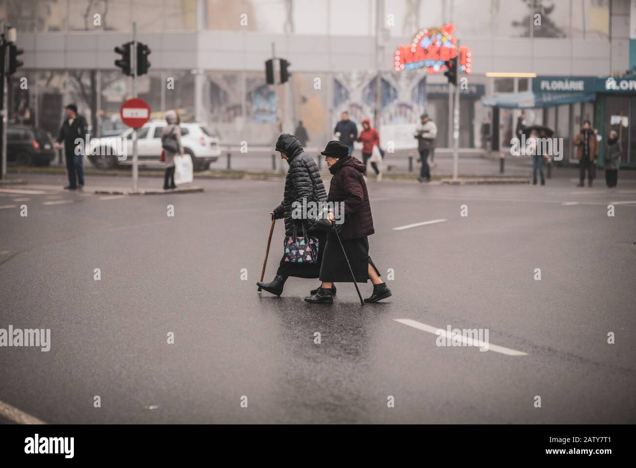 Bucarest, Roumanie - 20 décembre 2019: Deux vieilles femmes traversent illégalement la route au milieu d'un carrefour. Banque D'Images