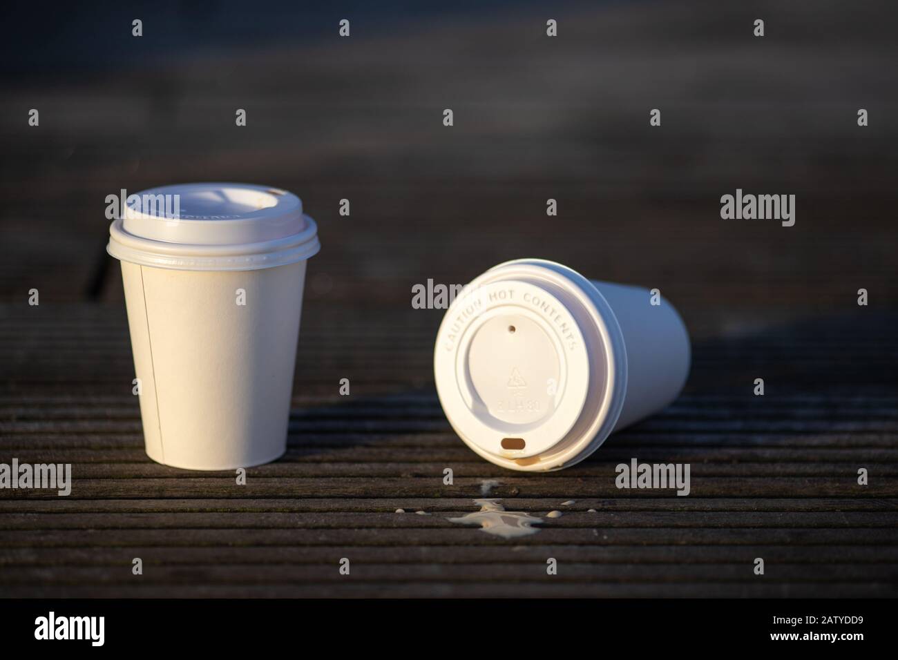 Gros plan de deux tasses en papier blanc à usage unique avec une surface vierge sur fond de bois, à l'extérieur le matin Banque D'Images