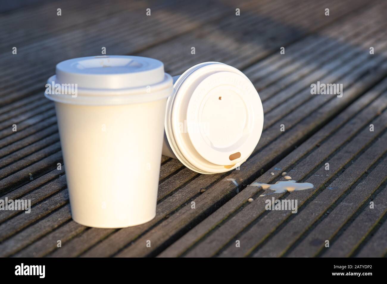 Gros plan de deux tasses en papier blanc à usage unique avec une surface vierge sur fond de bois, à l'extérieur le matin Banque D'Images
