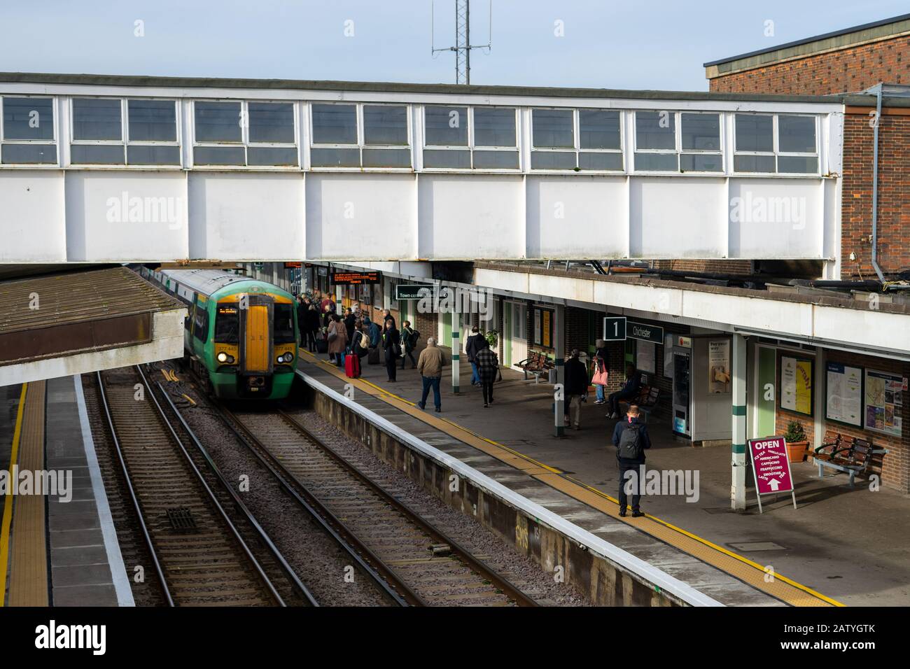 Les passagers des trains qui attendent sur une plate-forme de gare quand un train arrive Banque D'Images