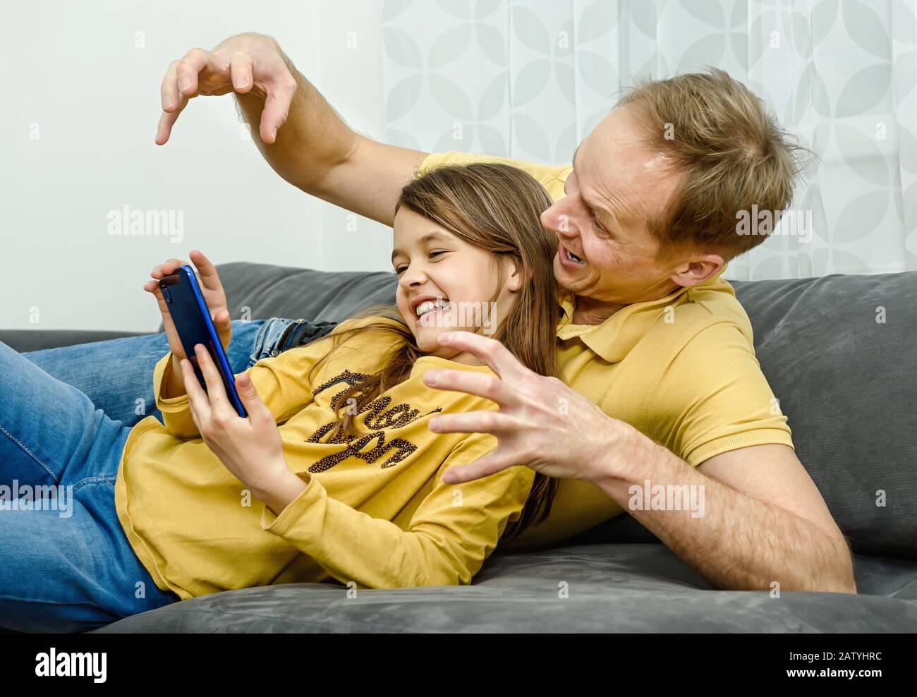 Père et doughter regarder dans le smartphone et avoir un excellent temps. Un concept de famille heureux. Banque D'Images