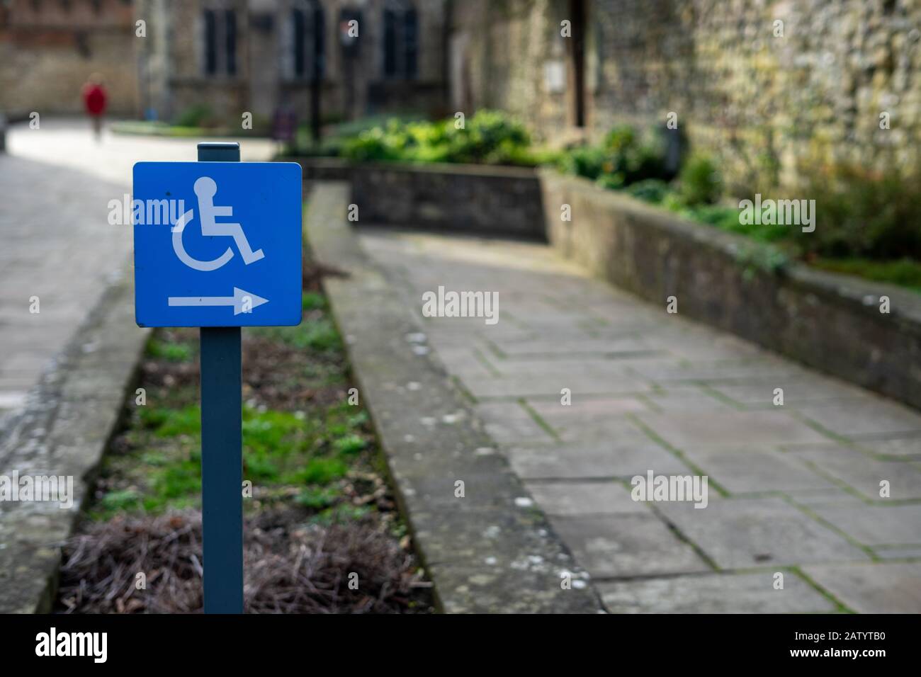 Un panneau désactivé pointant vers une rampe pour fauteuil roulant sur un chemin Banque D'Images