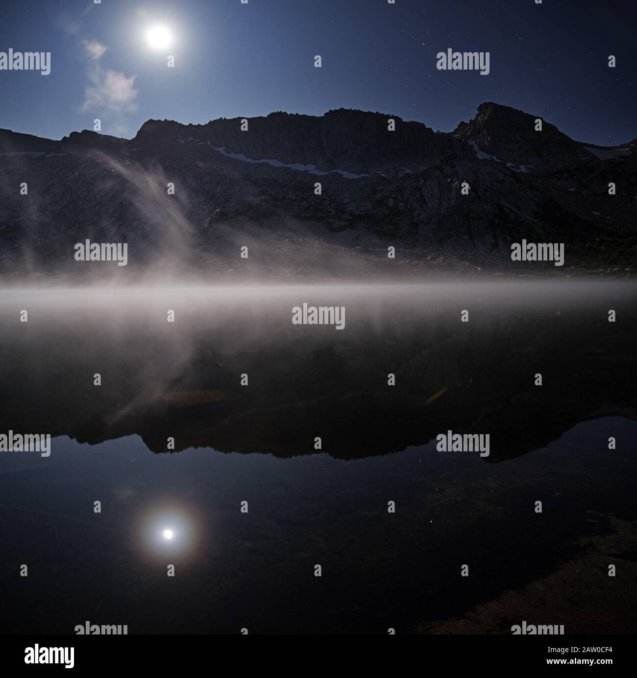 Un lac de Young misty éclairé par une lune presque pleine Banque D'Images