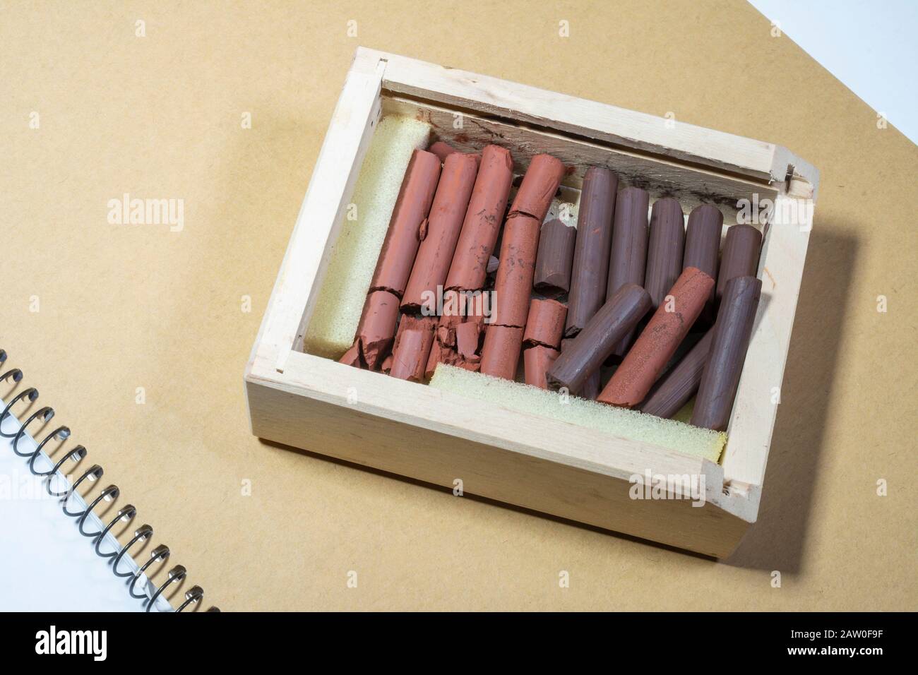 La sanguine et la sépia russes et les bâtonnets de dessin rouges dans une boîte en bois Banque D'Images