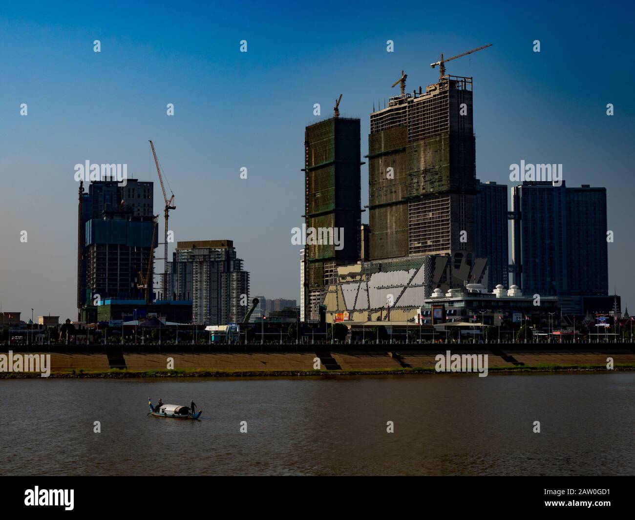 Un bateau traditionnel devant le boom de la construction le long du Mékong à Phnom Penh au Cambodge Banque D'Images