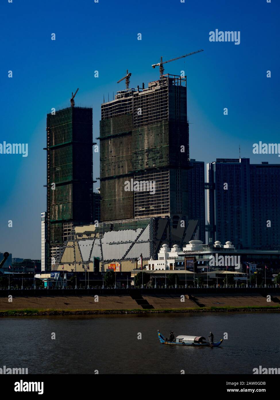 Un bateau traditionnel devant le boom de la construction le long du Mékong à Phnom Penh au Cambodge Banque D'Images