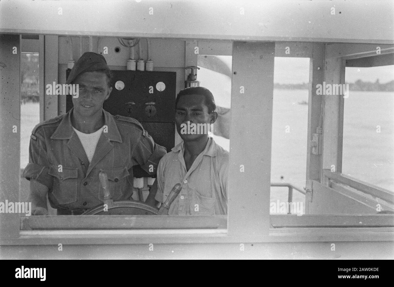 Simpang, Miroe, Gloembang, Praboemoelih soldat néerlandais régiment Stoottroepen derrière la roue dans un poste de pilotage d'un schp avec un homme indonésien (capitaine ?) Annotation: Dans la distance semble un quai à un ferry à voir pour être Date: 24 décembre 1947 lieu: Glumbang, Indonésie, Miru, Antilles Néerlandaises De L'Est, Prabumulih, Sumatra Banque D'Images