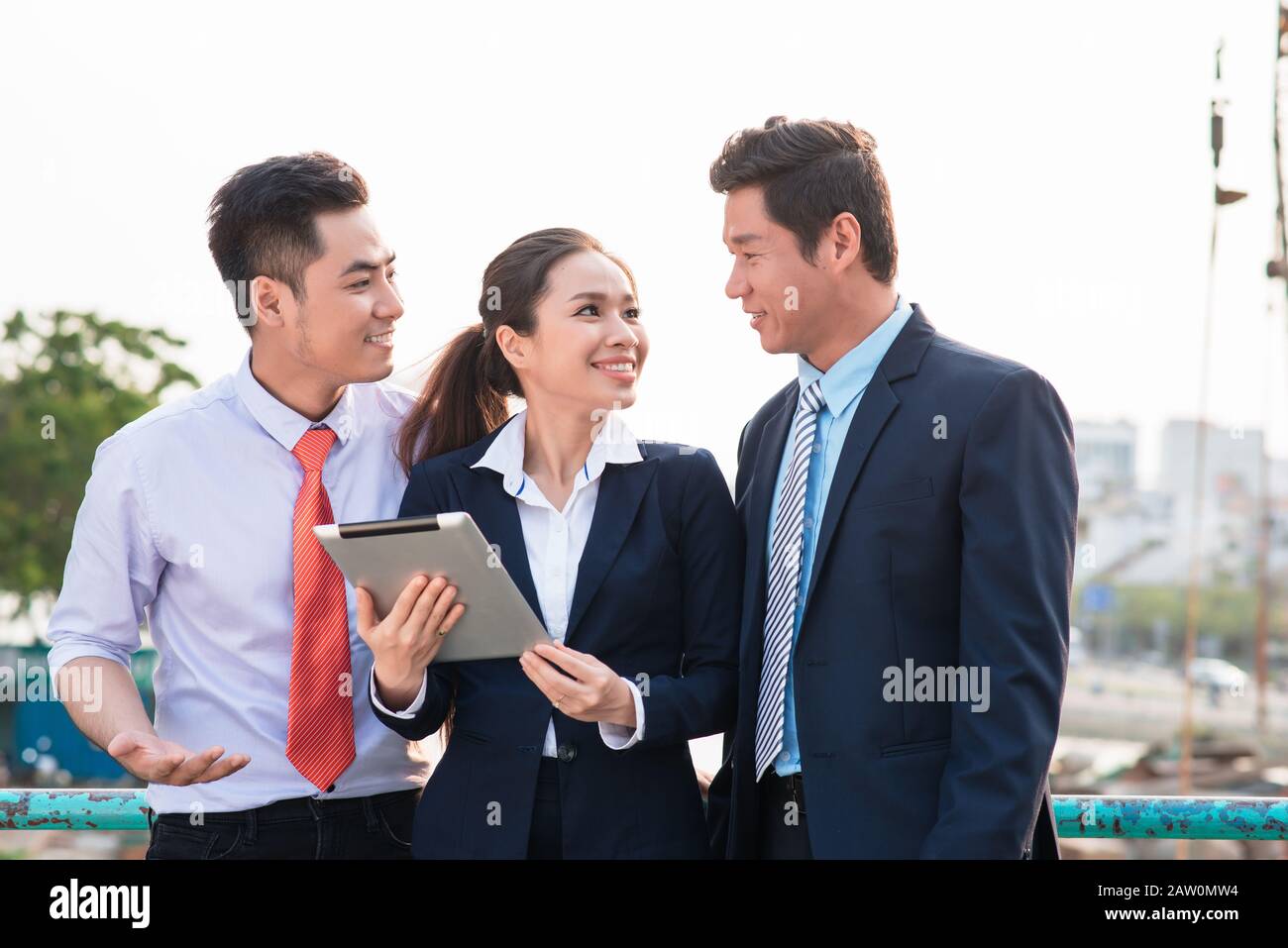 Asian businessman in suit montrant présentation en ligne sur tablette numérique à ses collègues alors qu'ils l'article Banque D'Images