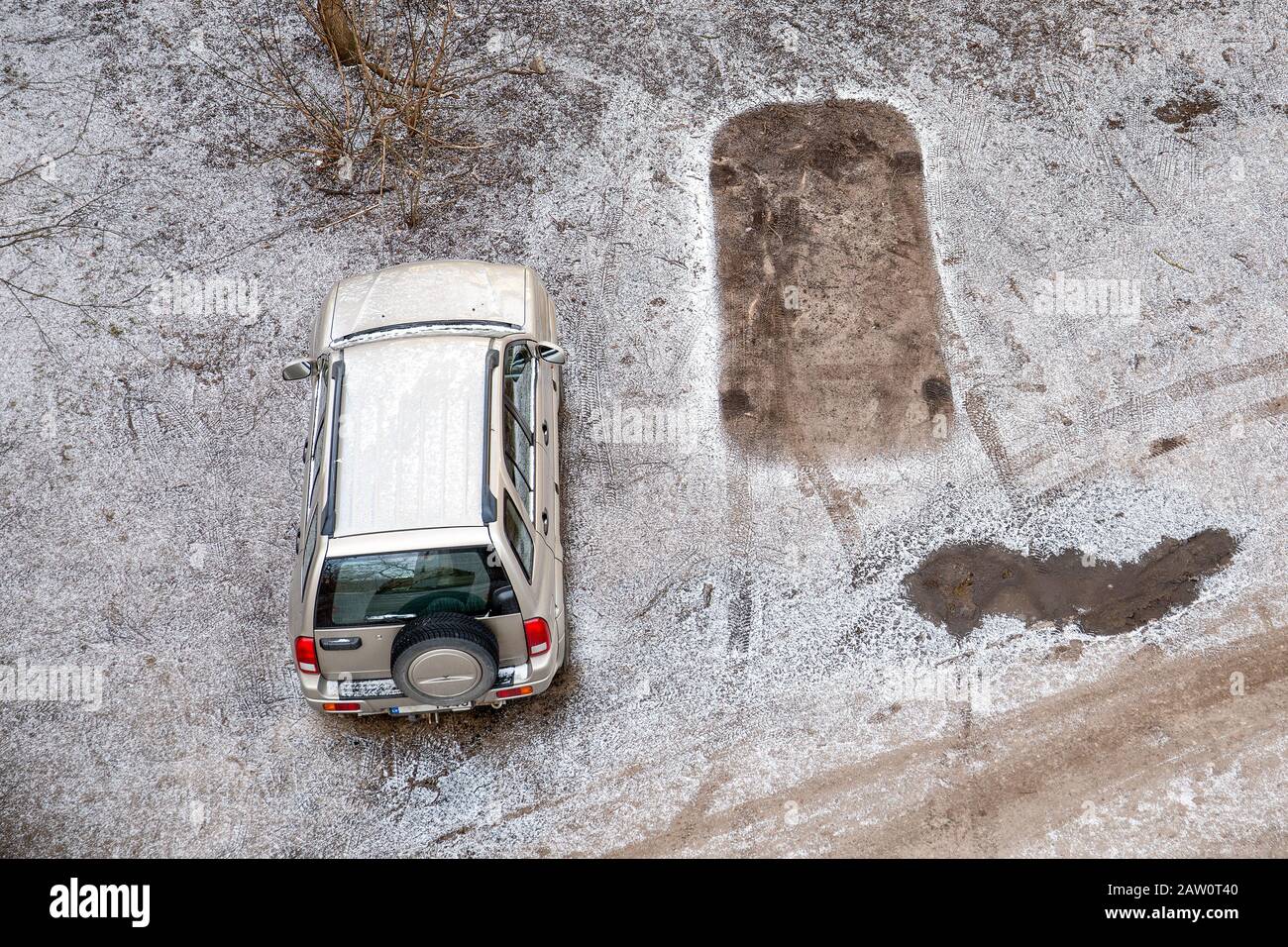 Une voiture et l'empreinte d'une autre voiture sur un terrain gelé et enneigé dans un endroit de paring. Concept pour l'espace de gauche, aller loin Banque D'Images
