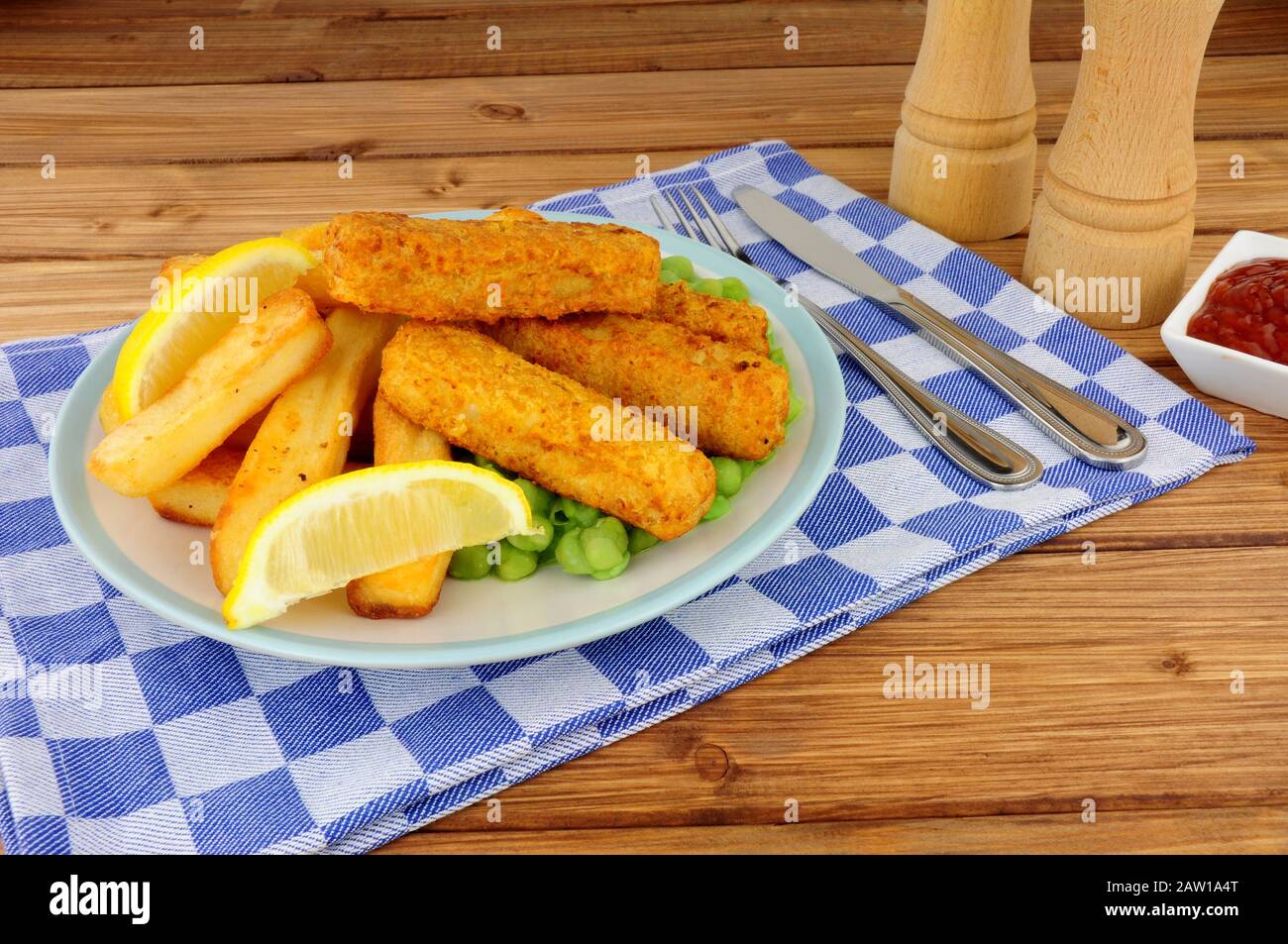 Les doigts de poisson et les chips couverts de pâte à frire sont repas avec des petits pois sur fond de bois Banque D'Images