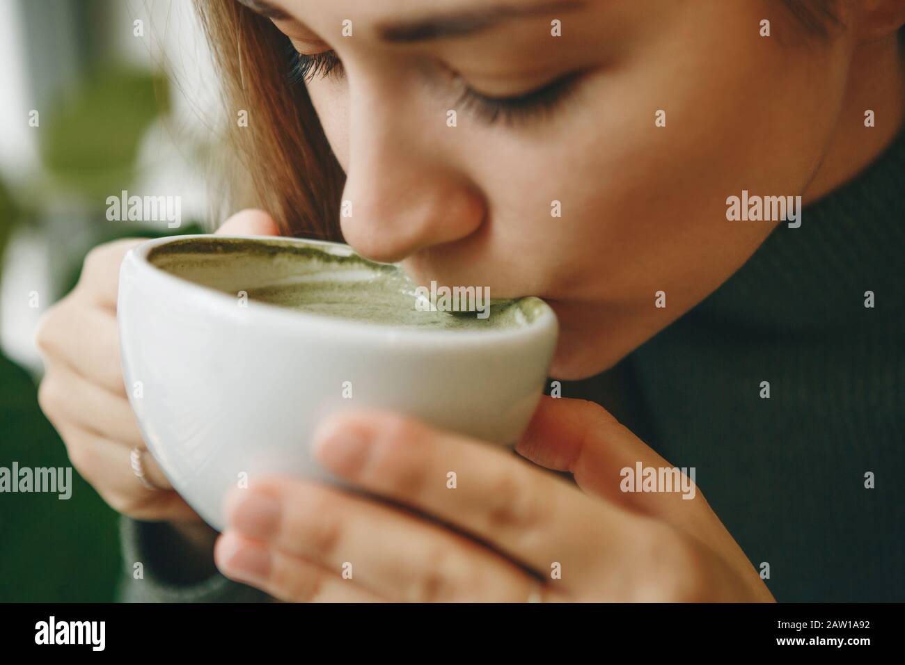 Close-up face ou portrait d'une fille qui boit sain et délicieux thé vert matcha latte Banque D'Images