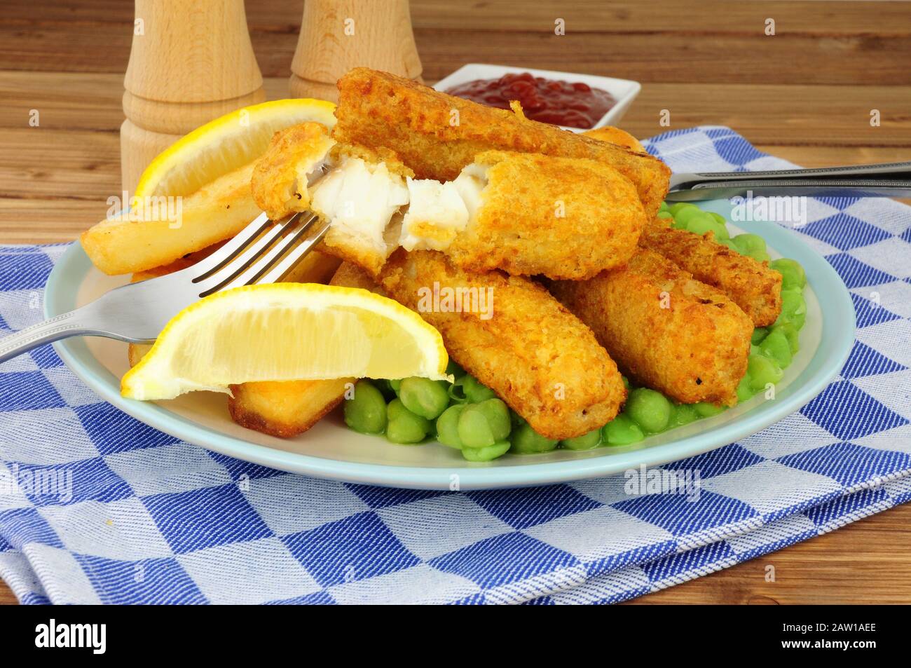 Les doigts de poisson et les chips couverts de pâte à frire sont repas avec des petits pois sur fond de bois Banque D'Images