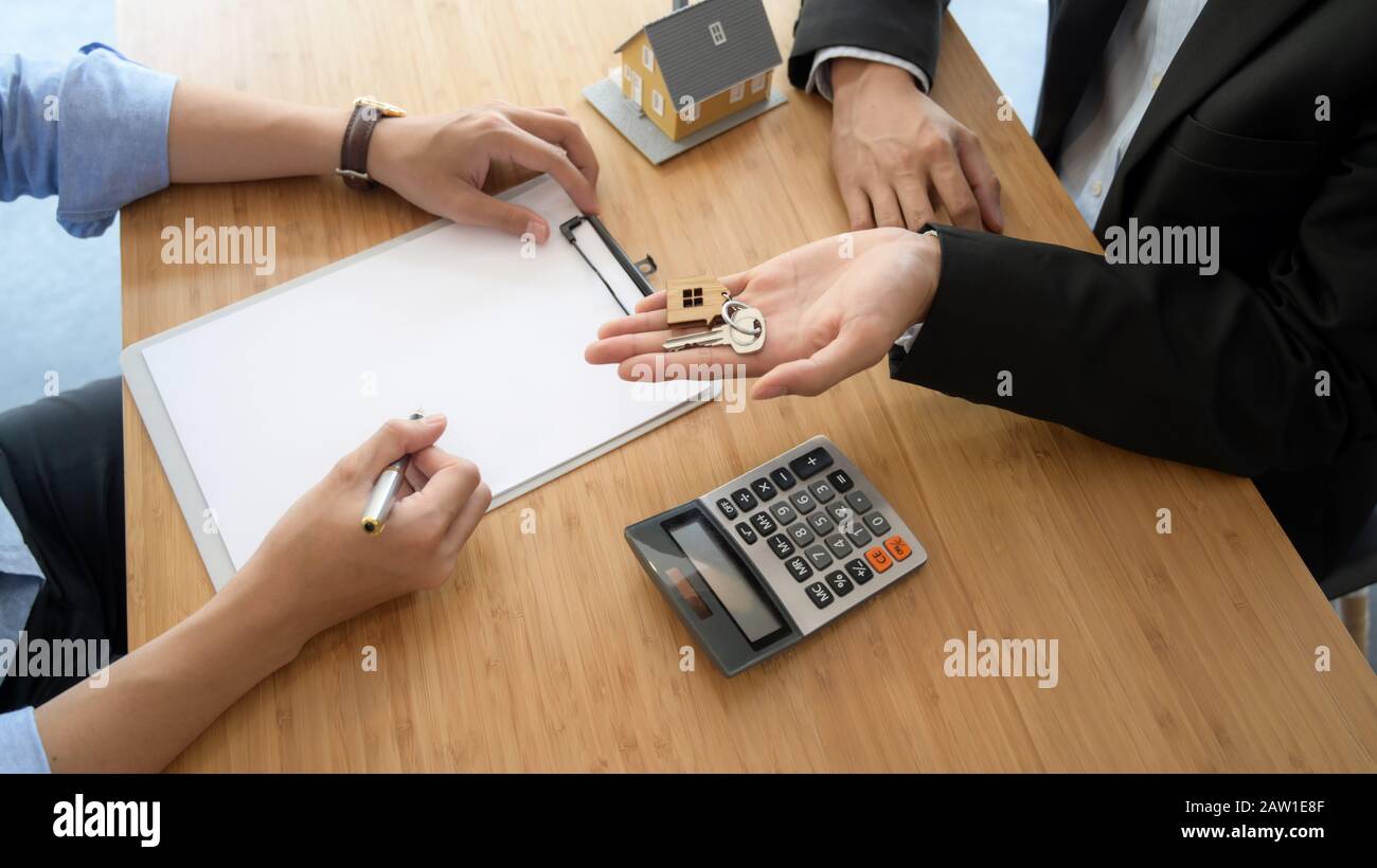 Vue de dessus de l'agent immobilier donnant la clé de maison à son client lors de la signature de l'accord de prêt à domicile Banque D'Images
