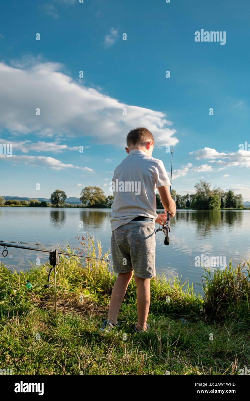 Pêche de garçon sur un lac. Magnifique étang à poissons près de Badin, Banska Bystrica, Slovaquie. Lieu de pêche. Soleil brillant sur l'étang de poissons en été. Banque D'Images