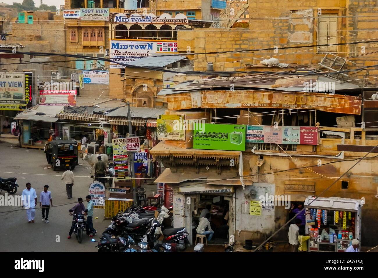 Jaisalmer, Rajasthan/Inde - 5 octobre 2013 : scène typique de rue indienne avec les habitants, divers véhicules et vaches qui erent dans les rues. Banque D'Images