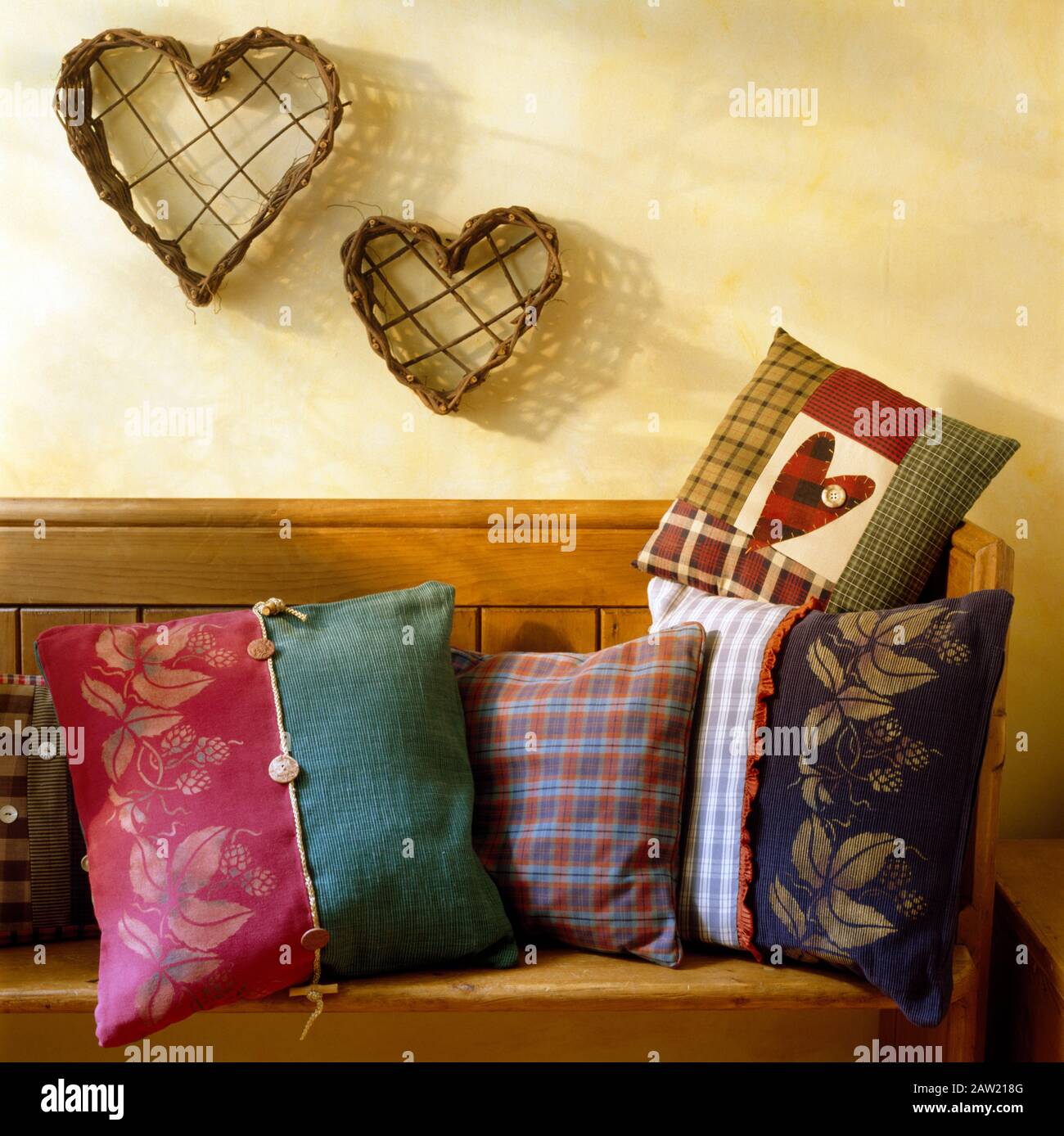 Ornements en forme de coeur twig mural au-dessus un vieux pin régler avec coussins avec un motif au pochoir raisin Banque D'Images