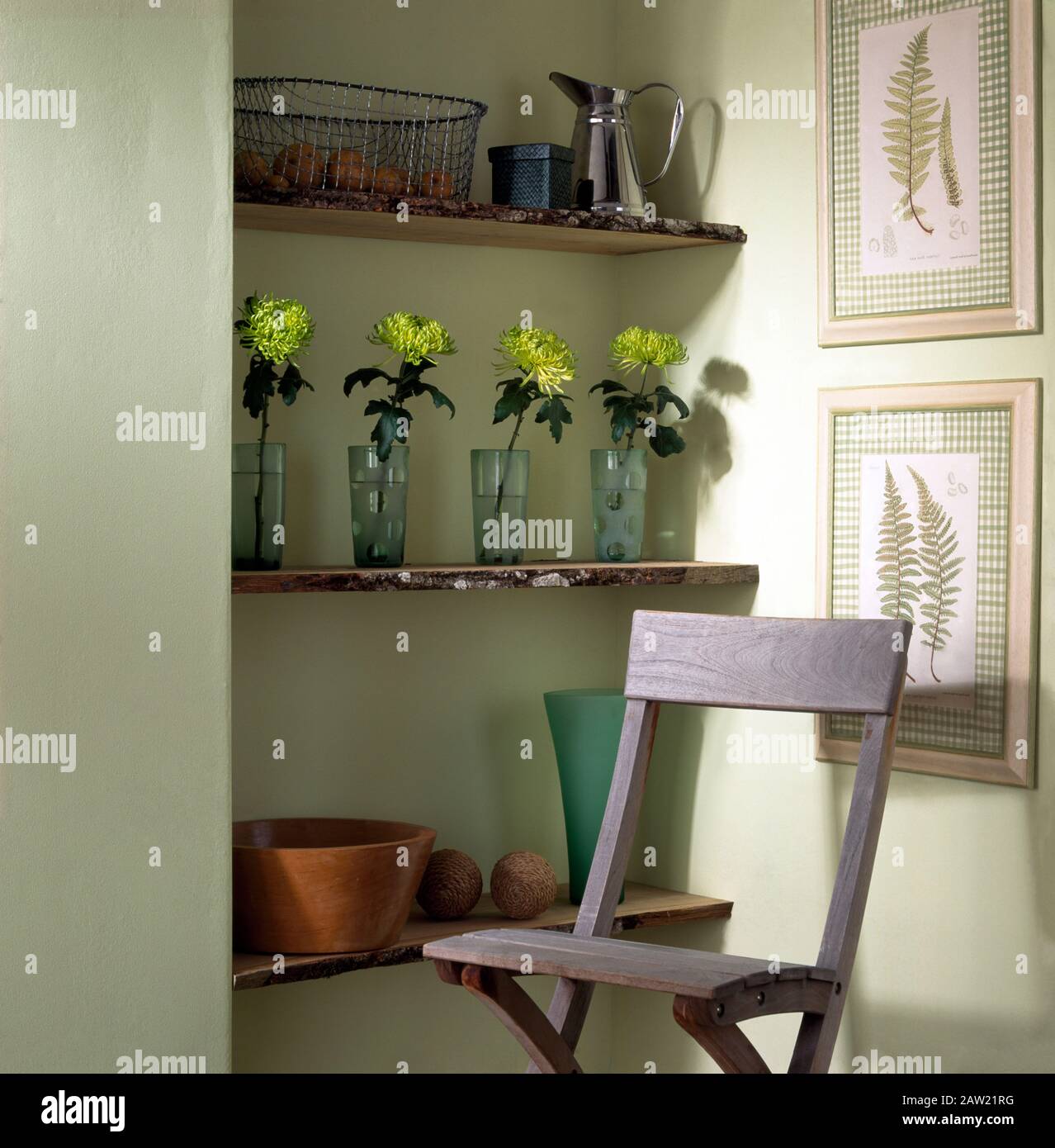 Lavé Lime chaise en bois en face de l'alcôve simple étagères avec chrysanthèmes vert dans une rangée de vases de verre Banque D'Images