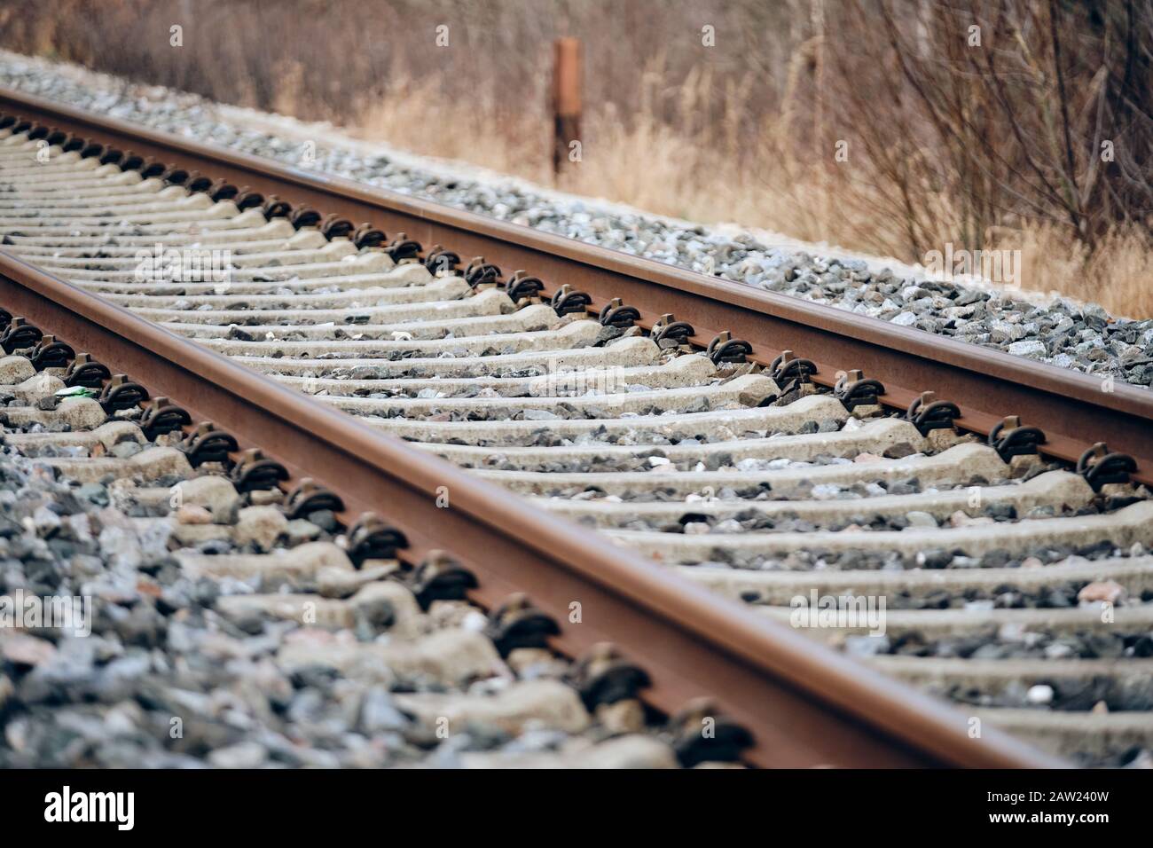 Gros plan d'une ligne de chemin de fer légèrement rouillée avec des traverses de chemin de fer en béton sur un ballast de voie en pierre concassée dans un environnement naturel. Vu à Germ Banque D'Images