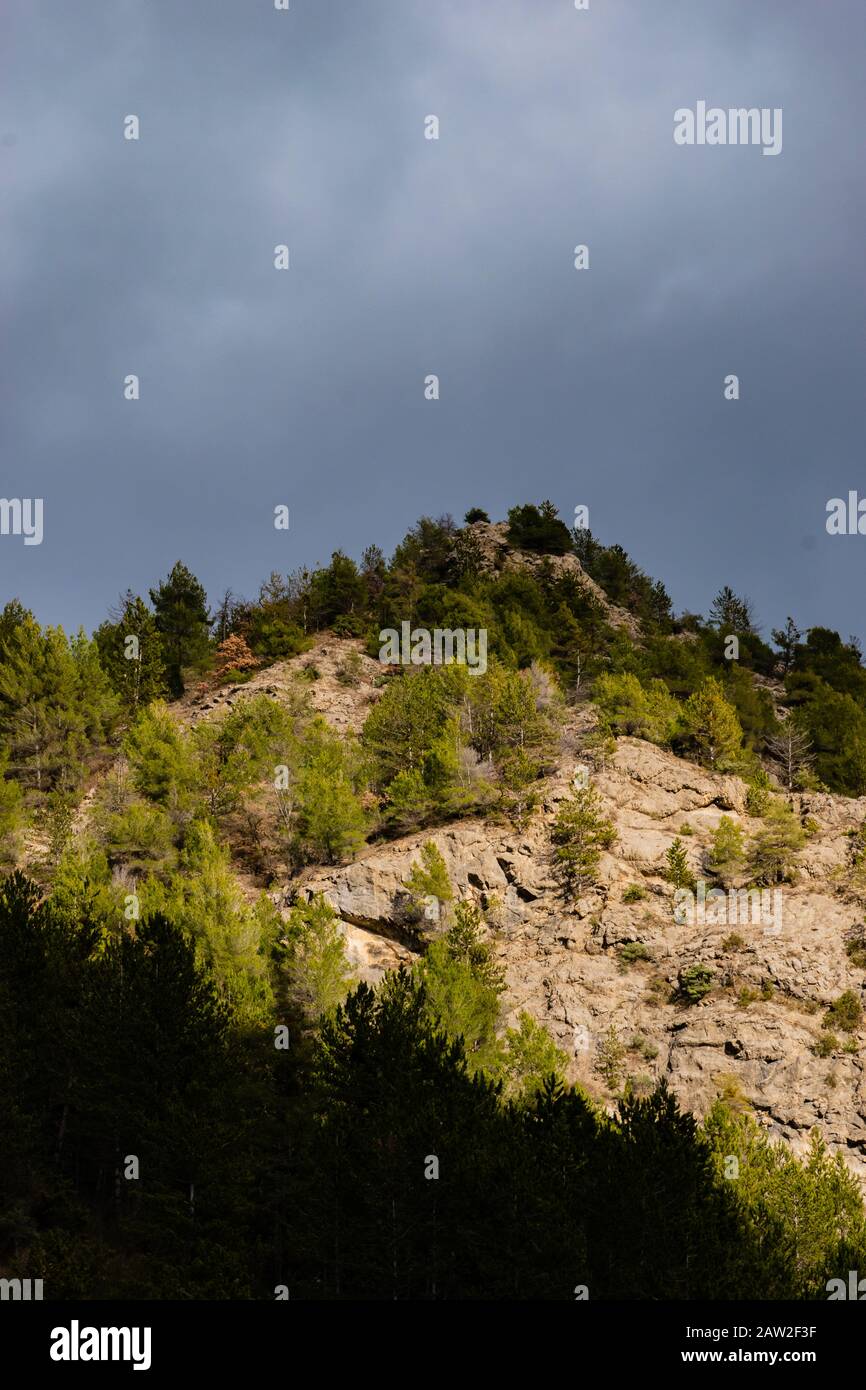 La vue à contraste élevé des Alpes françaises basses sous la lumière chaude du soleil sur le fond du ciel sombre nuageux Banque D'Images