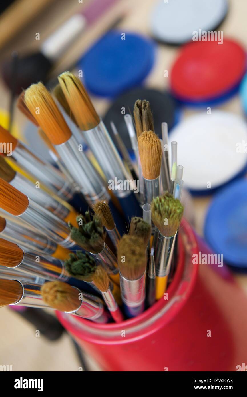Peindre les pinceaux dans un pot avec différentes peintures colorées à l'arrière-plan Banque D'Images
