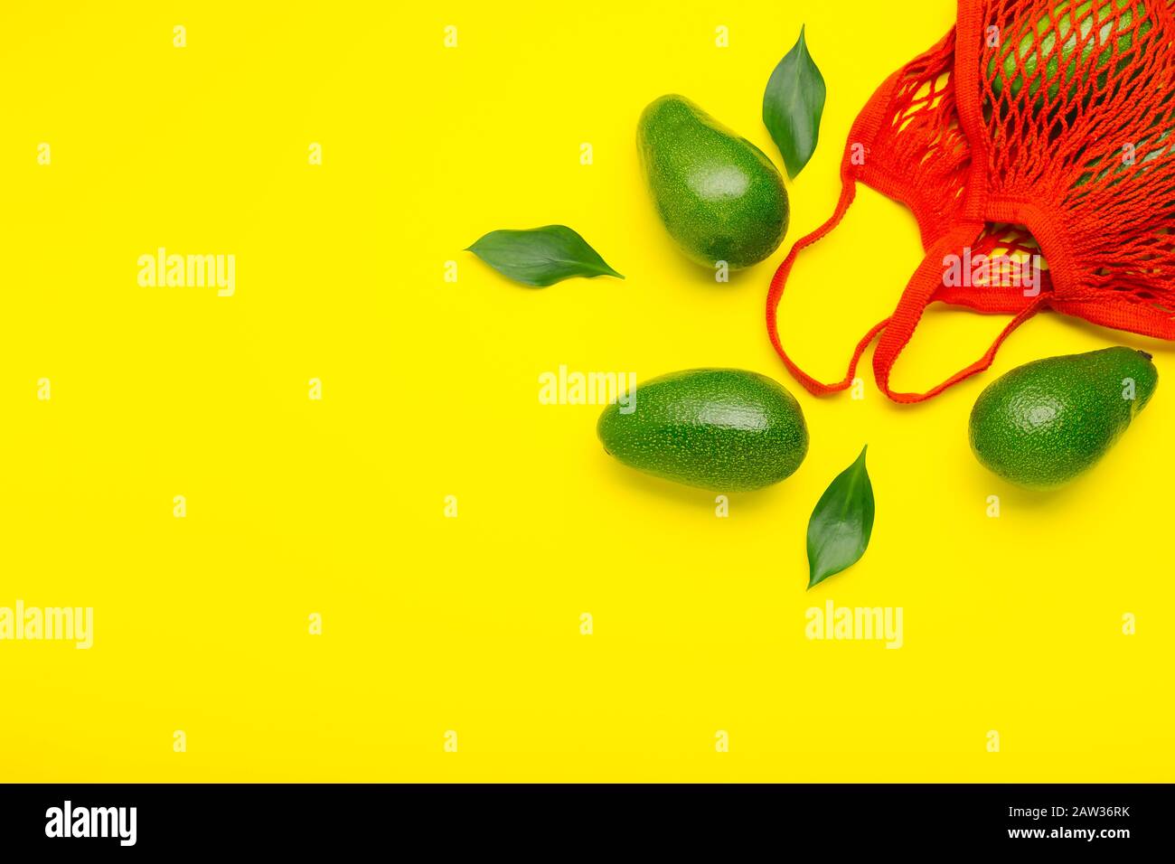 Avocats fruits dans un sac écologique en mesh rouge réutilisable. Sac en mesh recyclé pour fruits ou légumes. Concept d'achat sans plastique, zéro déchet. Pose plate minimale Banque D'Images