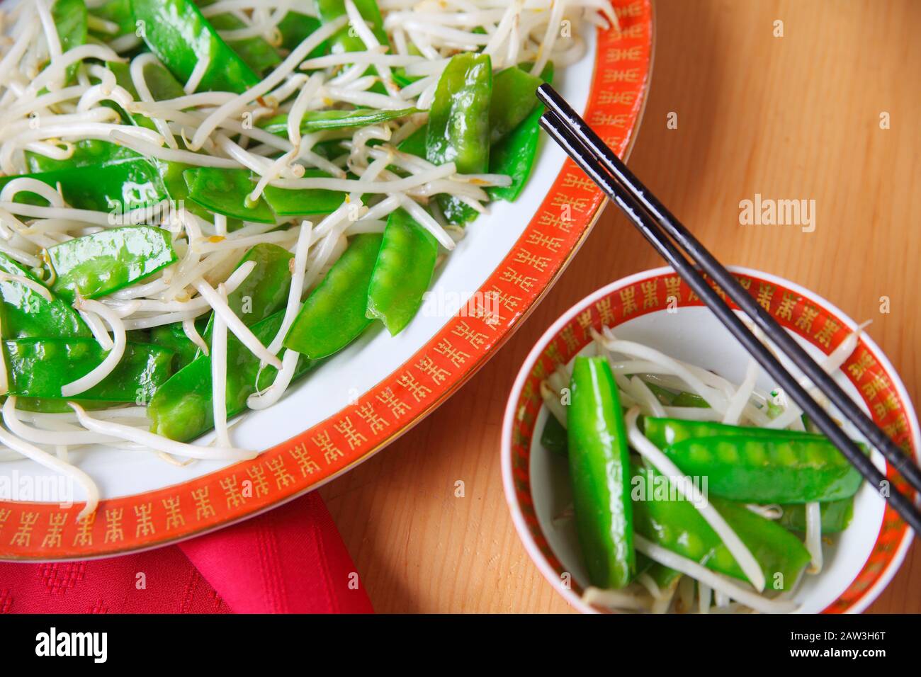 Assiette de légumes sautés et d'un servant dans un bol chinois avec des baguettes Banque D'Images