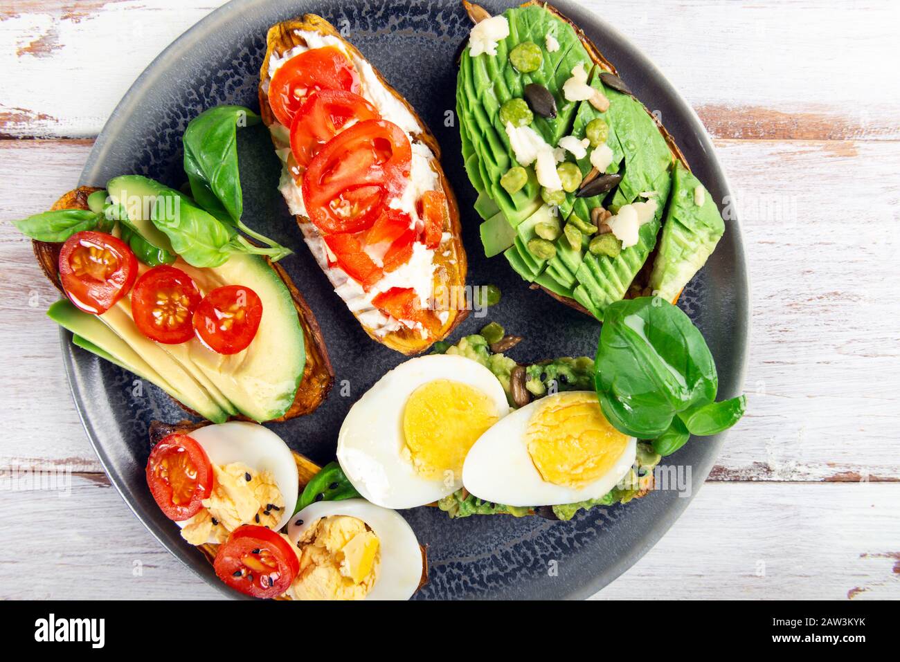 Toasts de patate douce avec avocat, œufs durs, tomates et graines de sésame sur fond rustique blanc. Concept de repas sain. Cuisine propre, plats du Pescetarian, vue sur le dessus Banque D'Images