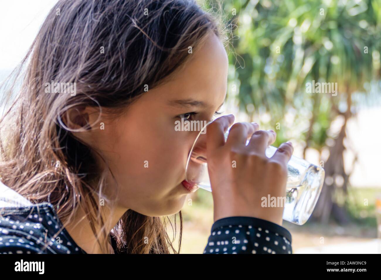 Tween girl boit de l'eau avec un fond de plage flou Banque D'Images