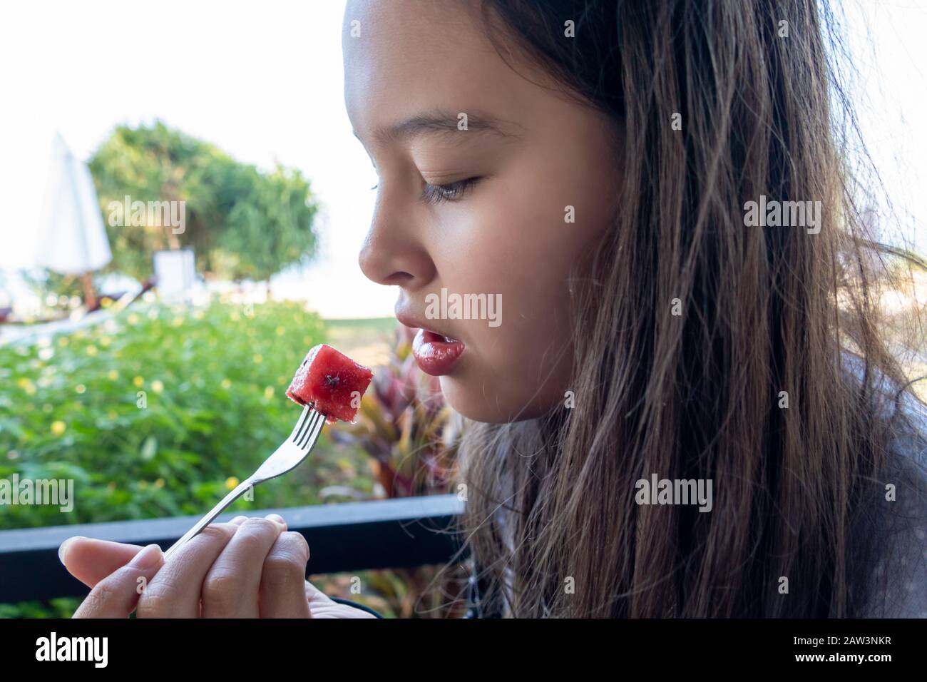 La jeune fille asiatique américaine Tween mange du pastèque avec une fourchette Banque D'Images