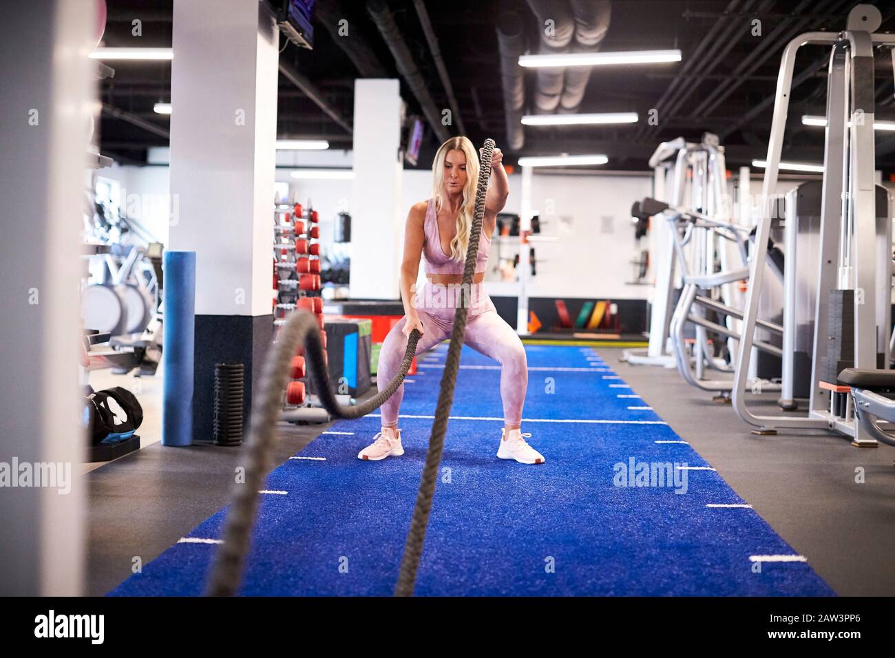 Une femme s'exerçant avec des cordes de combat sur le gazon à la salle de gym. Banque D'Images