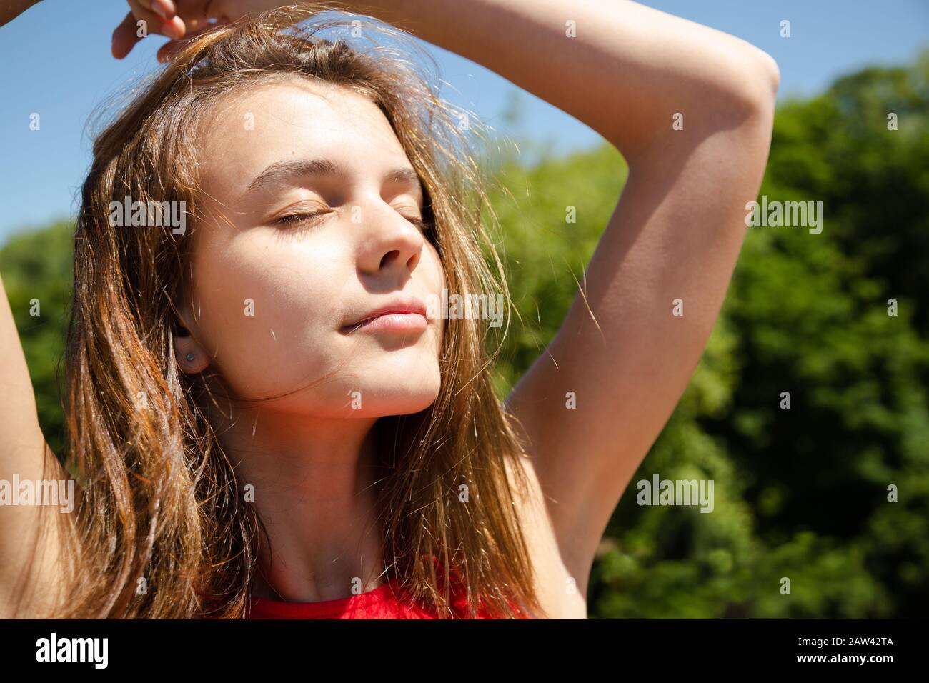 Jeune belle femme en haut rouge profitant du soleil avec les yeux fermés au  printemps ou en été Photo Stock - Alamy