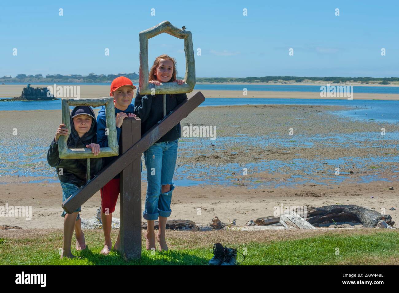 Les frères et sœurs se sont alignés sur les cadres en bois du parc Siletz Bay Park pour leur photo avec des roches intertidales en arrière-plan pendant leurs vacances à Lincoln City, Banque D'Images